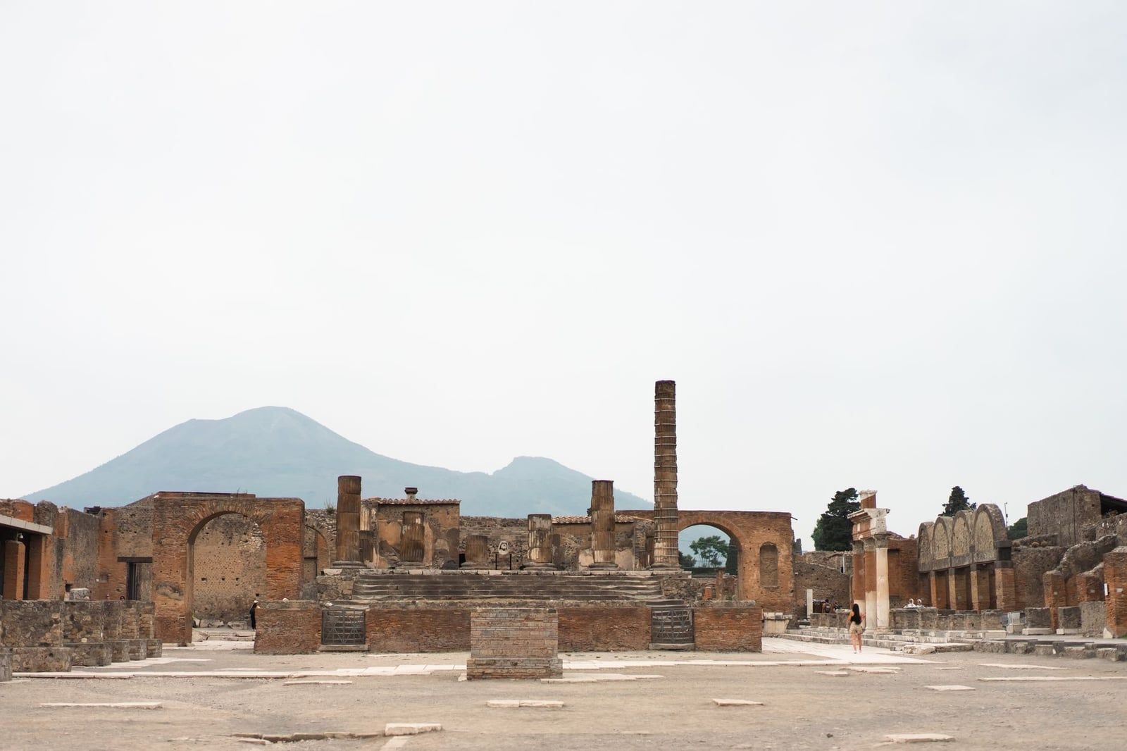 The ancient Roman ruins of the Forum at Pompeii with Mount Vesuvius standing in the background.