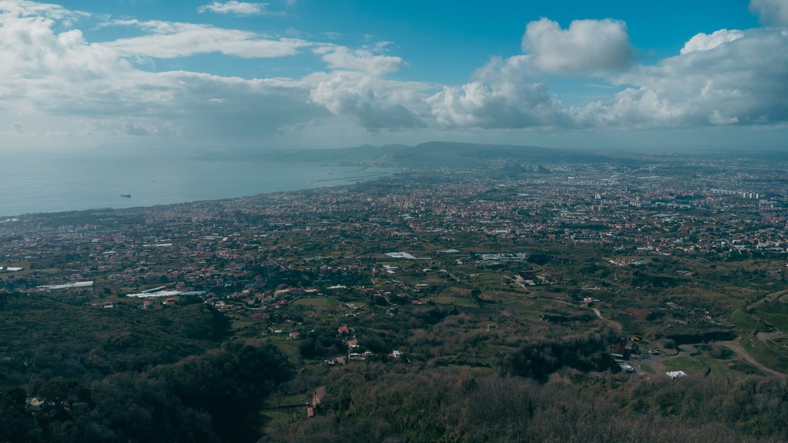 Panoramic view overlooking the Bay of Naples and coastal settlements from the slopes of Mount Vesuvius.