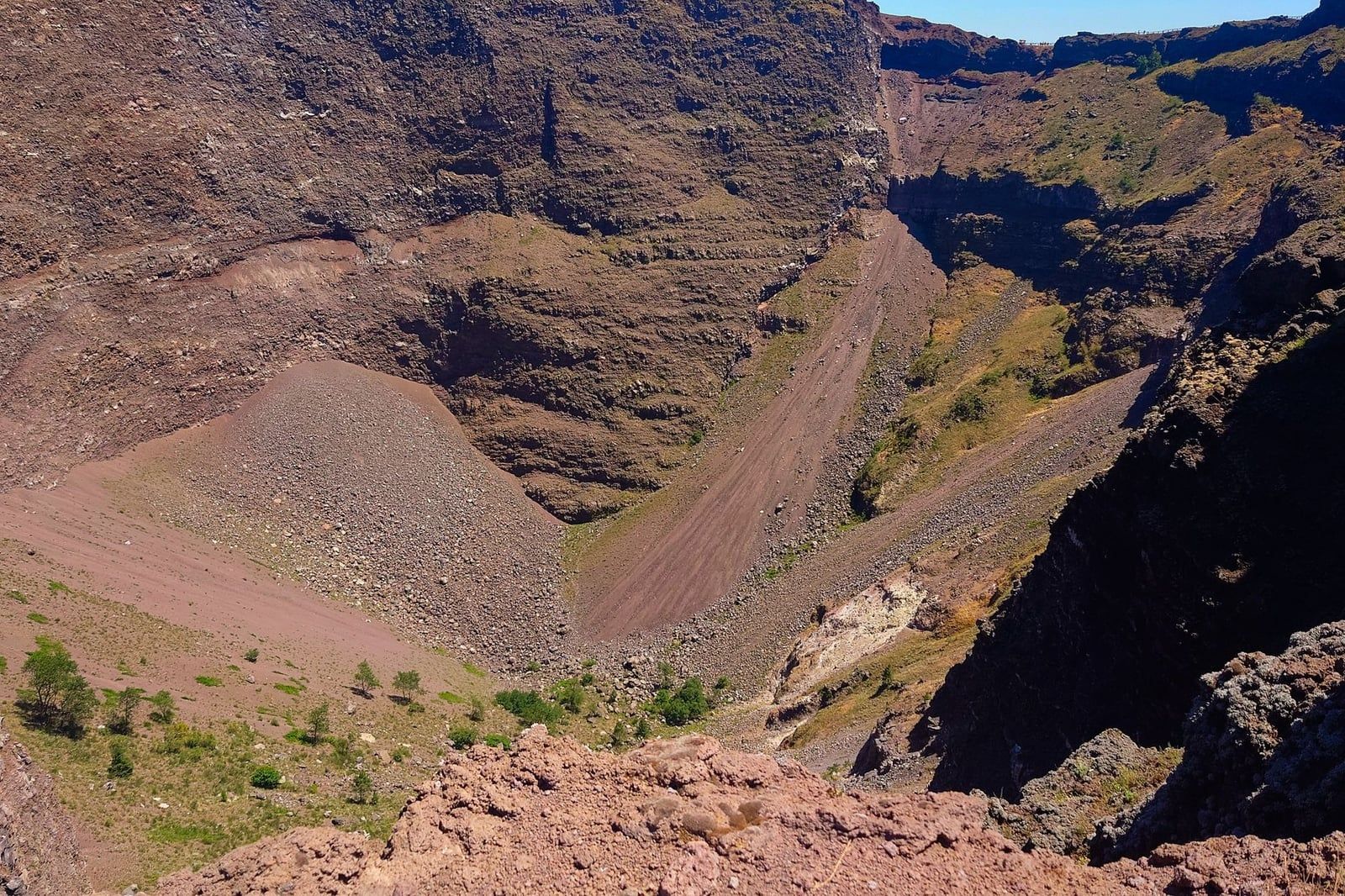 Steep, rocky walls and loose scree slopes plunge into the summit crater of Mount Vesuvius.