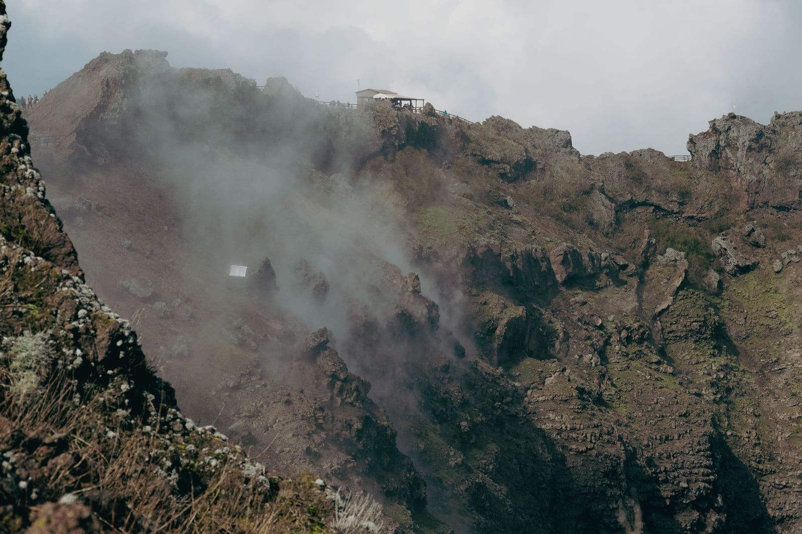 Steam rises from fumaroles along the rugged rocky walls inside the crater of Mount Vesuvius.